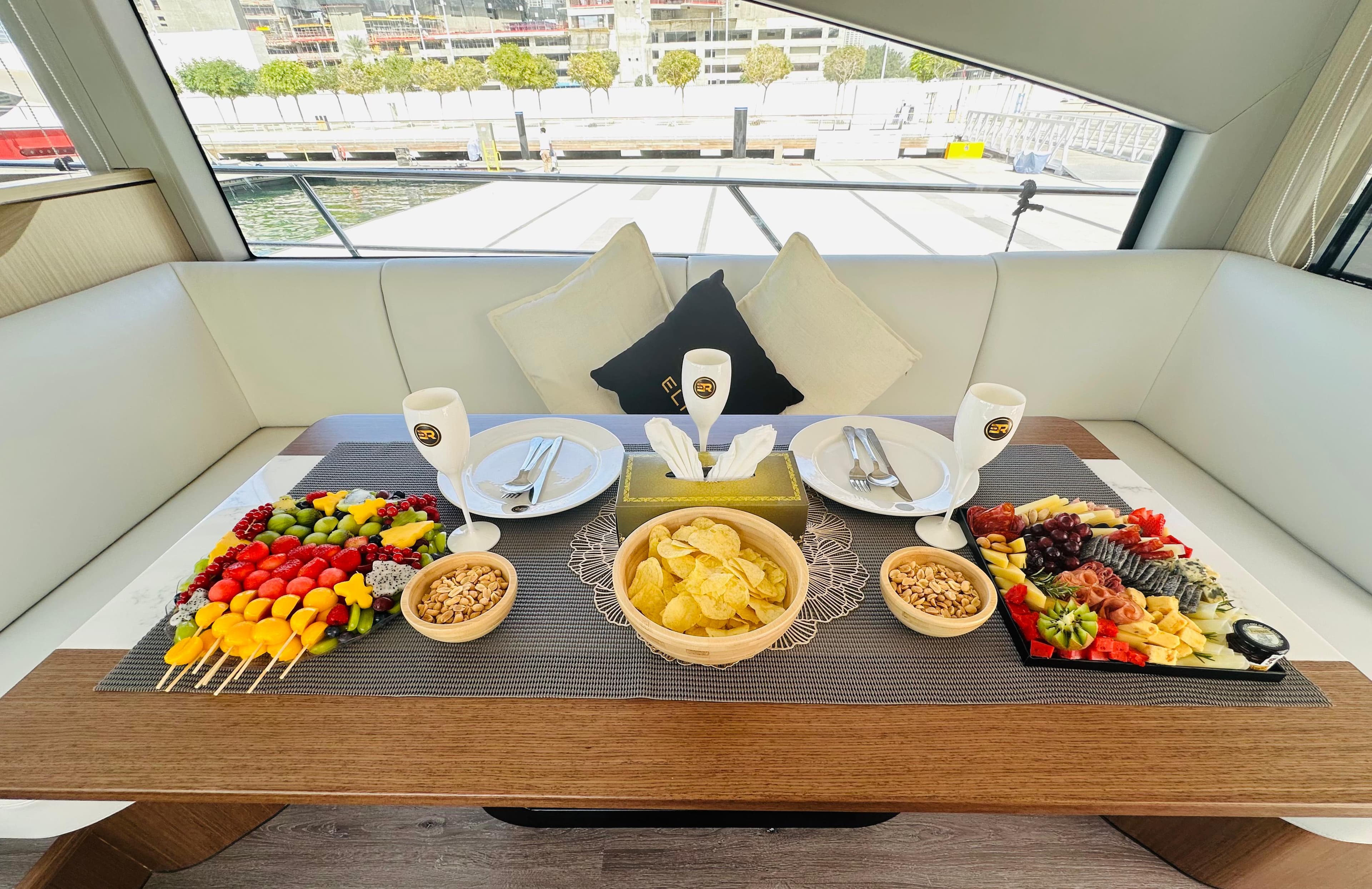 Luxury yacht interior dining setup with gourmet fruit platters and fine tableware for corporate event