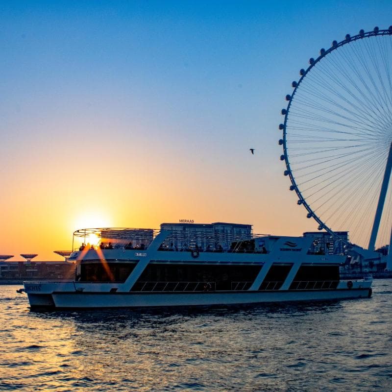 Yacht sunset cruise passing Ain Dubai ferris wheel at golden hour